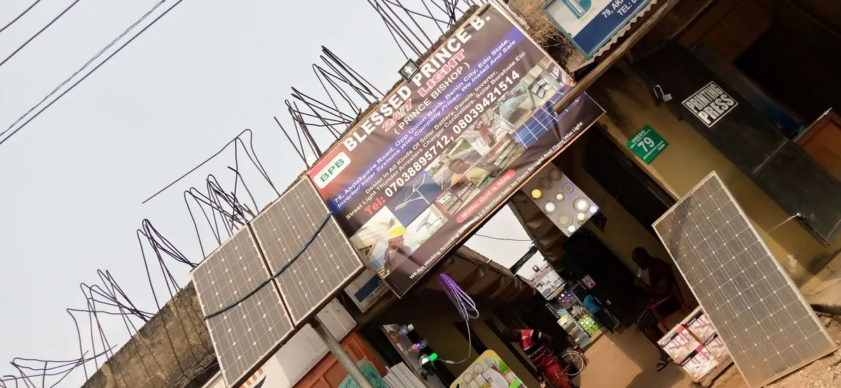 The Blessed Prince B. 24/7 Light signboard above the shop at 79 Akpakpava Road, with solar panels on display